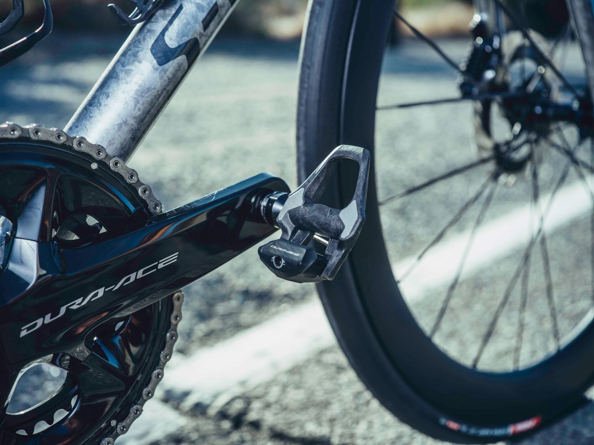 Close-up of a bicycle’s rear derailleur and chain beside a wheel.