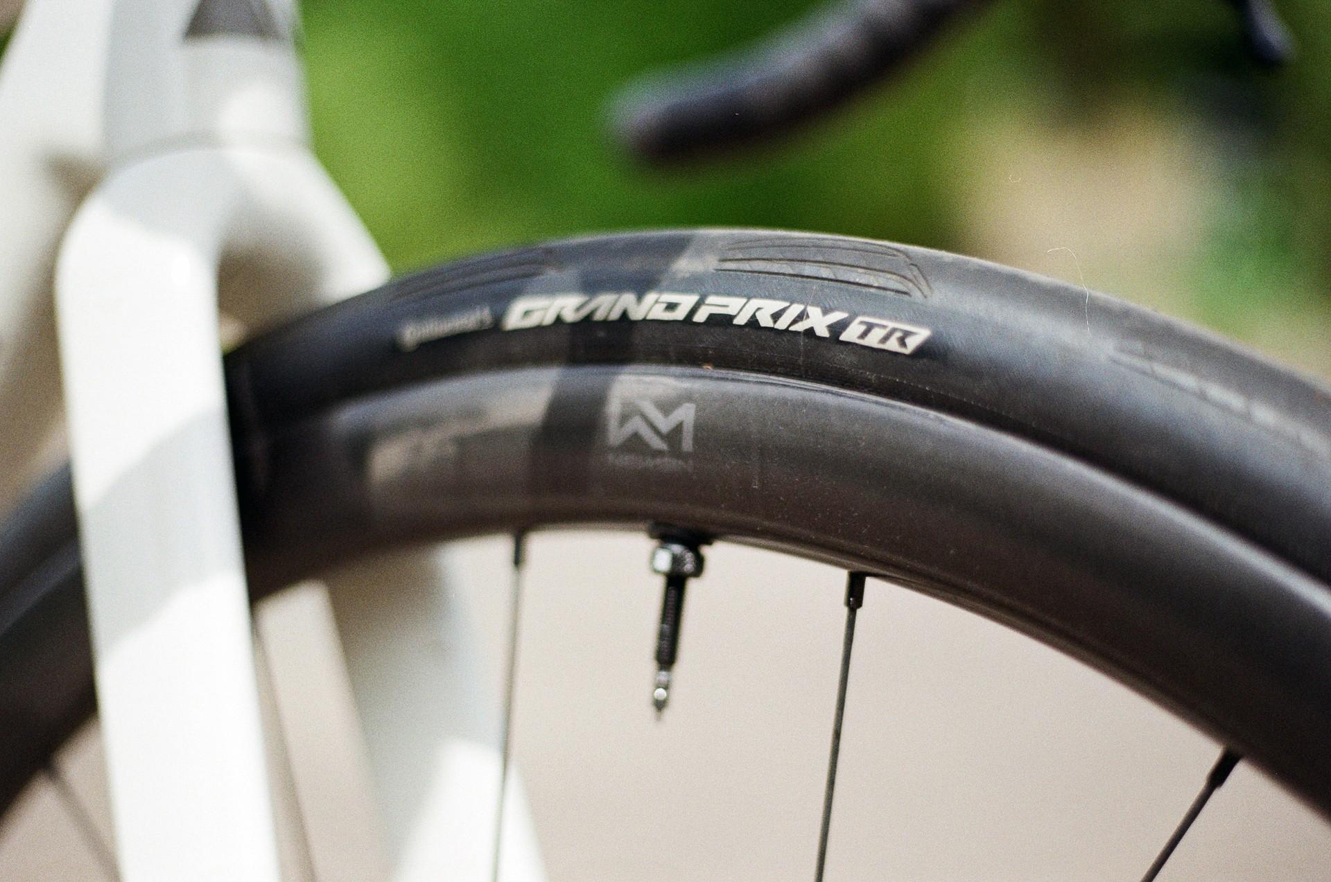 Close-up of a racing bike’s front wheel and tire branding at speed during a road event