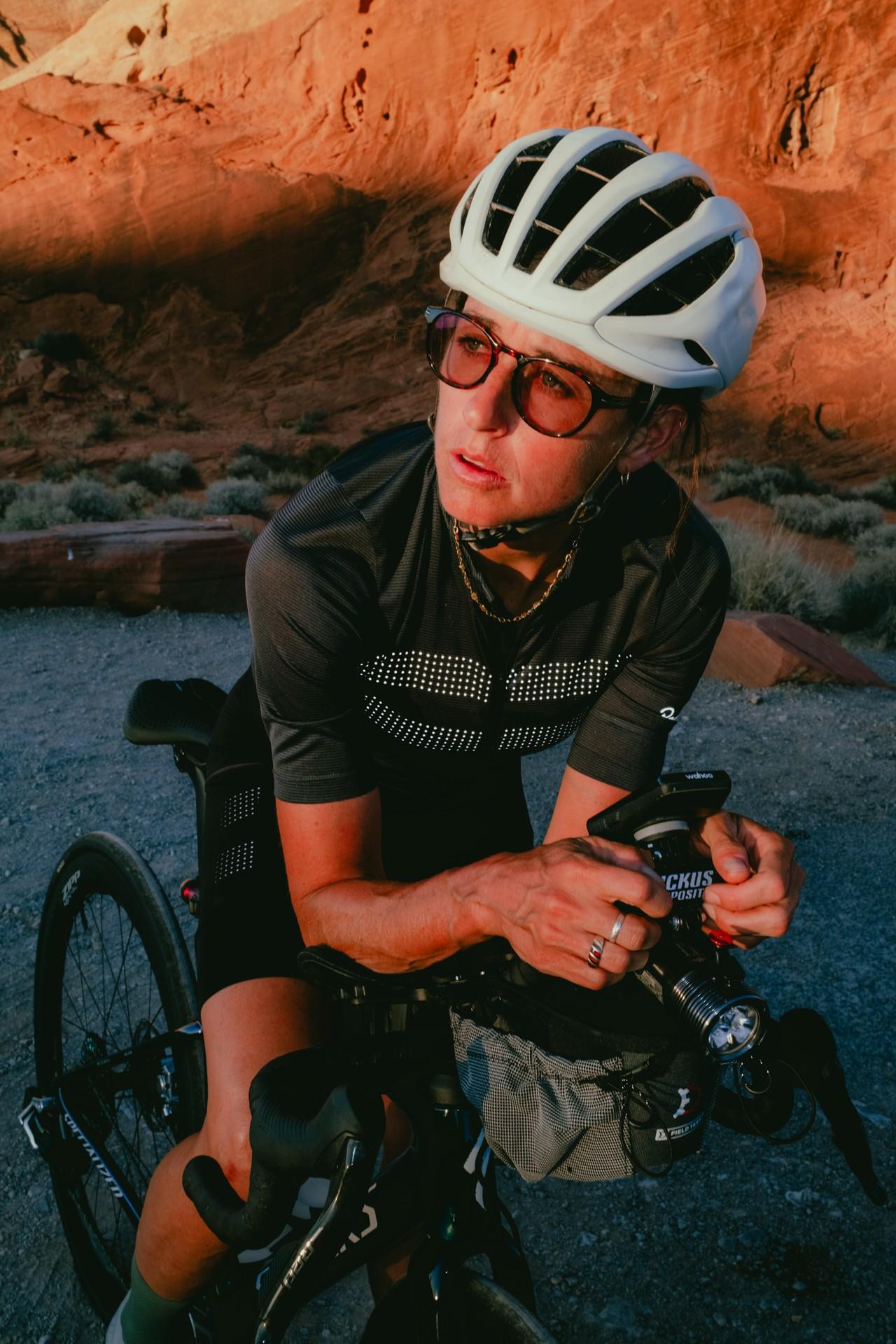 Cyclist posing while holding a mountain bike near a desert canyon road