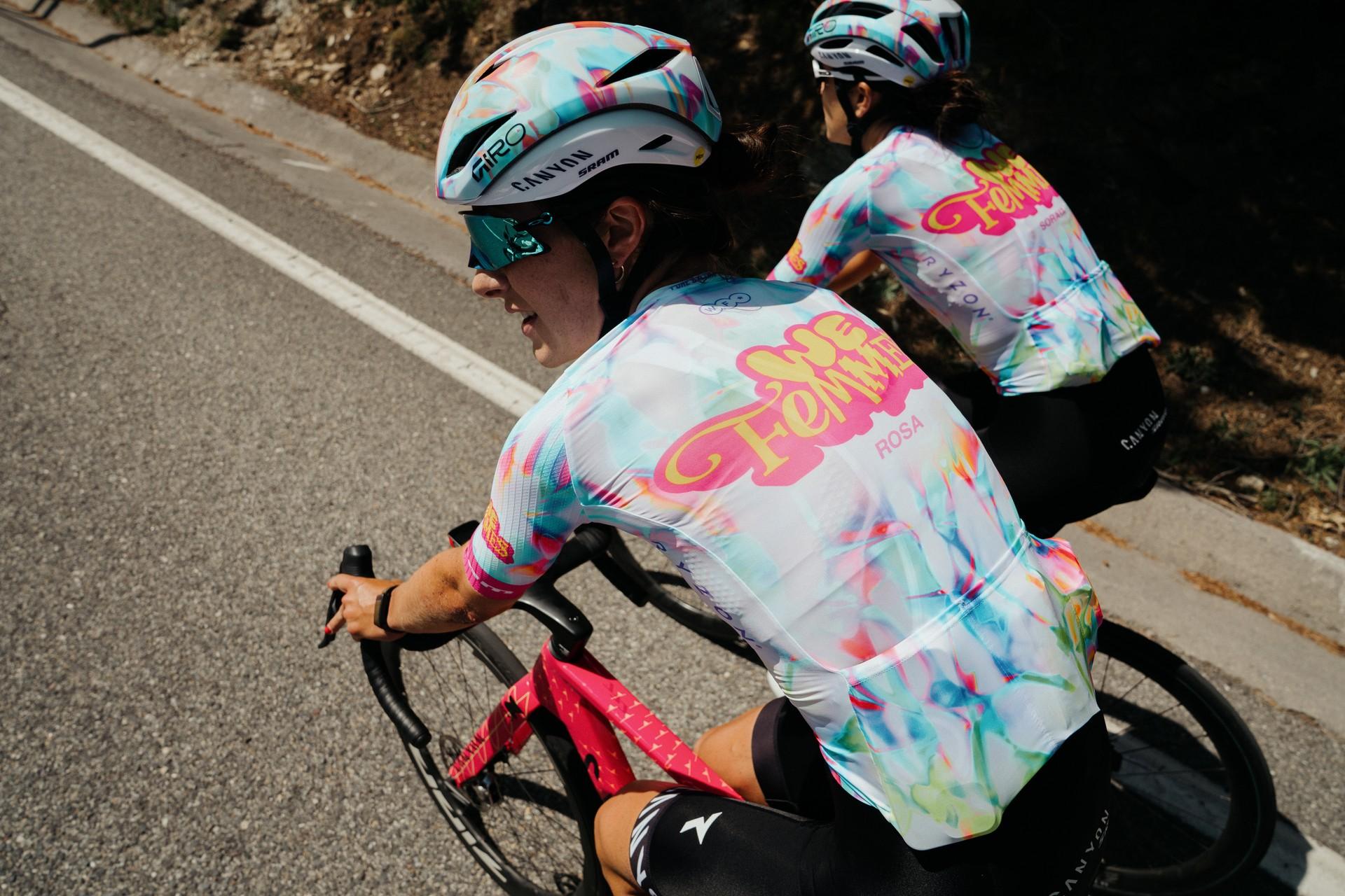 Two cyclists in matching patterned kits ride close together during a road race sprint.