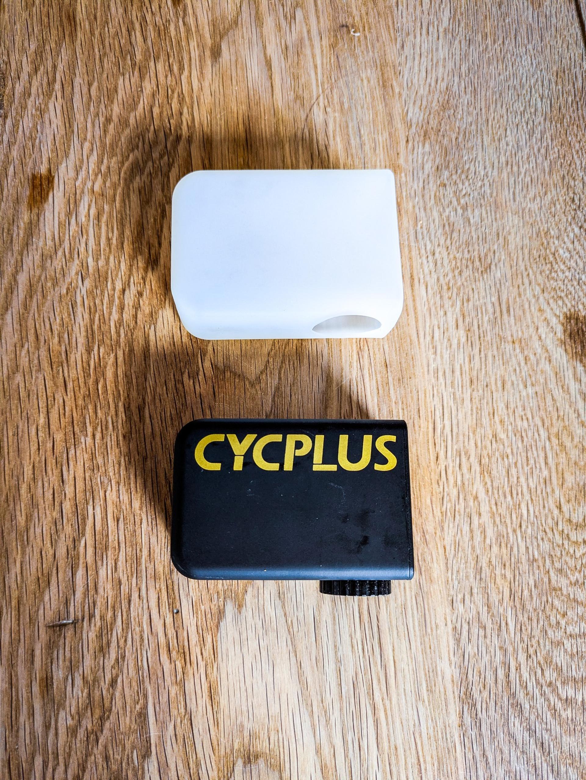 Cycplus AS2 Ultra e-pump beside its white silicone sleeve on a wooden surface