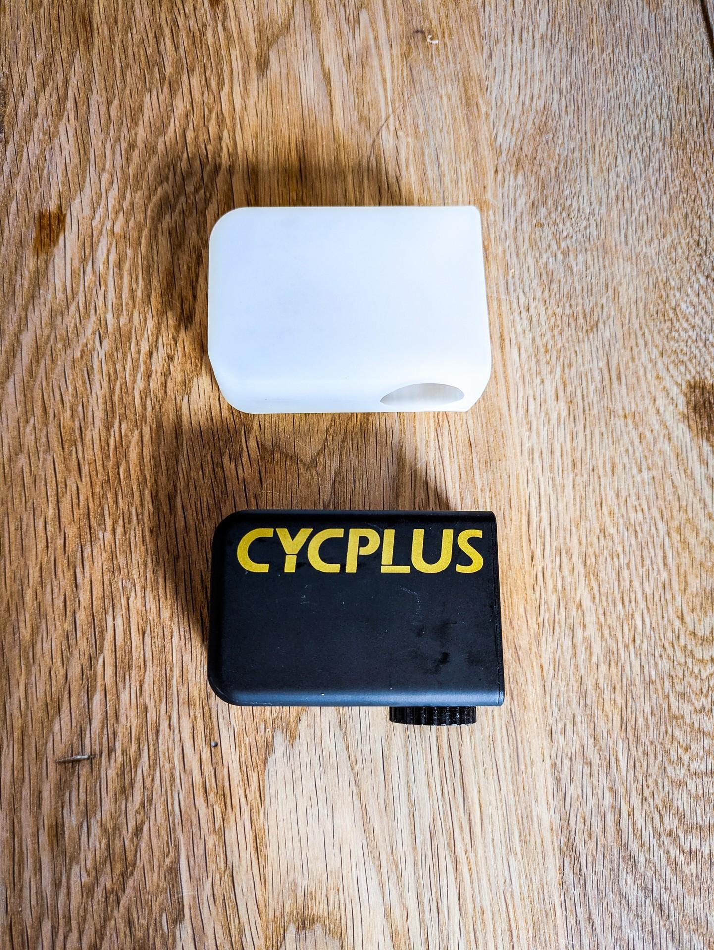 Cycplus AS2 Ultra e-pump beside its white silicone sleeve on a wooden surface