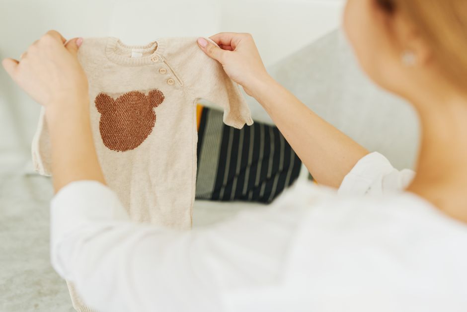 A happy baby wearing a soft, white organic cotton onesie, looking content in a sunlit nursery.