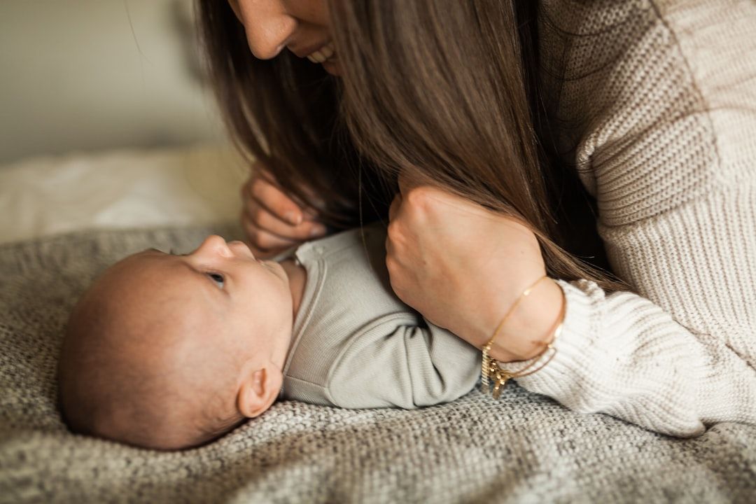 A parent gently holding a newborn baby dressed in a soft, white cotton onesie.