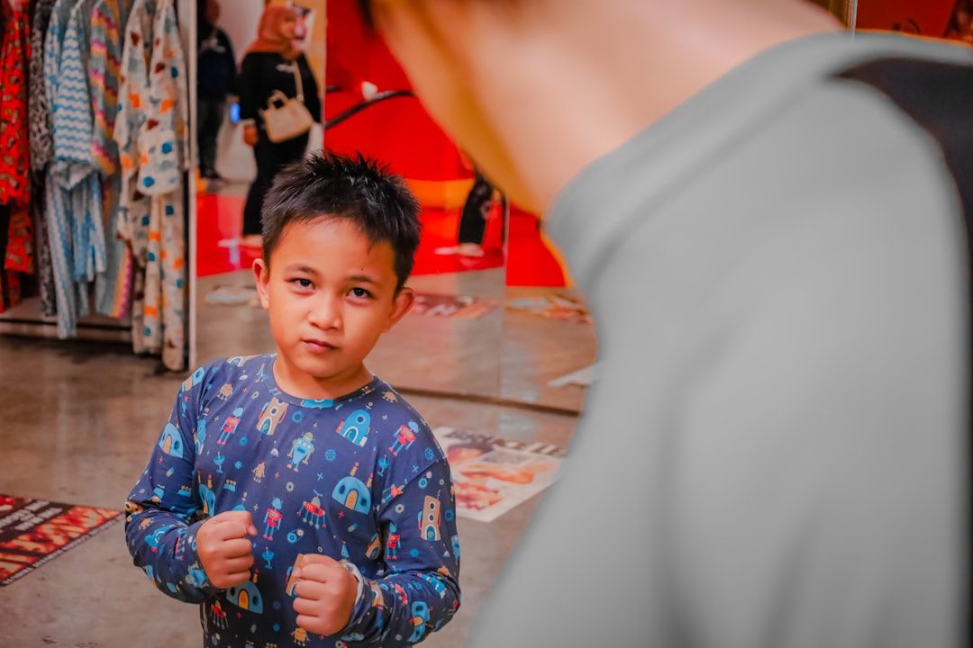 A young boy smiles while looking at a rack of colorful t-shirts.