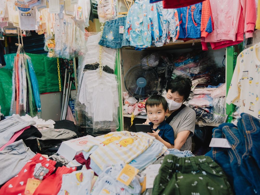 A young boy is happily holding up a t-shirt he likes.
