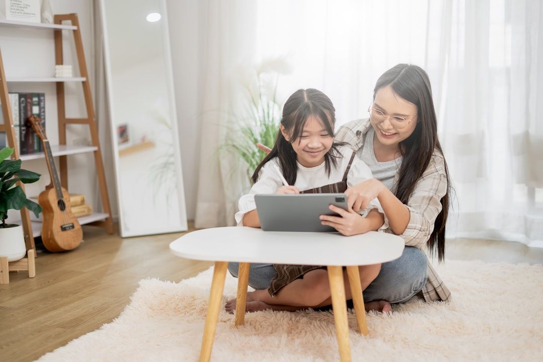 A mother and her young son are smiling while looking at clothes on a tablet.