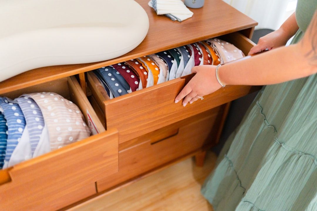 A selection of soft, pastel-colored newborn baby clothes neatly arranged on a wooden changing table.