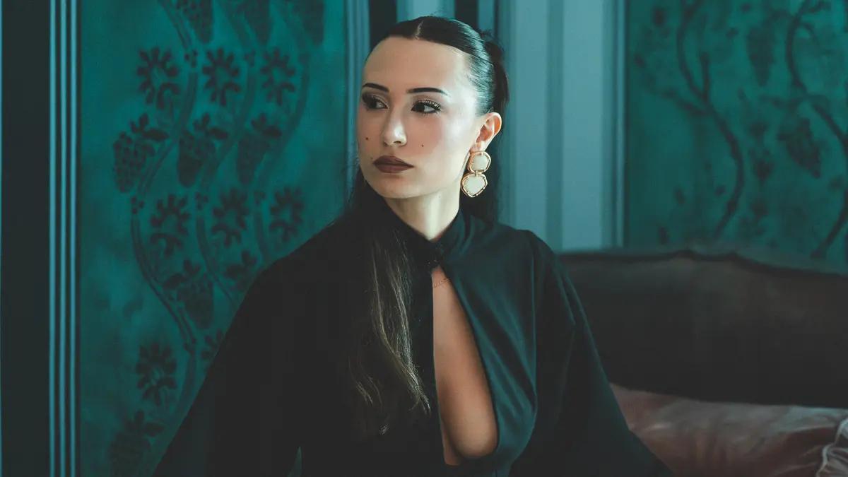 Photographie de mode par Karl Eska pour TactileDesigns. Mannequin Ilona Vanco - - Regina dans les salons du château Acar de Bedou à Cars. Robe noire structurée, boucles dorées, lumière tamisée sur fond de décor Second Empire. Portrait éditorial, Bordeaux.