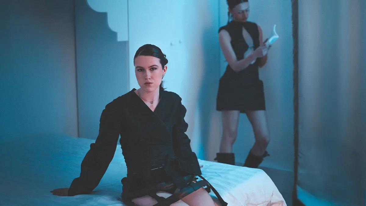Photographie de mode par Karl Eska pour TactileDesigns. Lea Bizet au premier plan, Lena en arrière-plan. Deux pièces sombres structurées dans un décor minimaliste éclairé en bleu froid. Portrait éditorial, mise en scène à deux sujets.