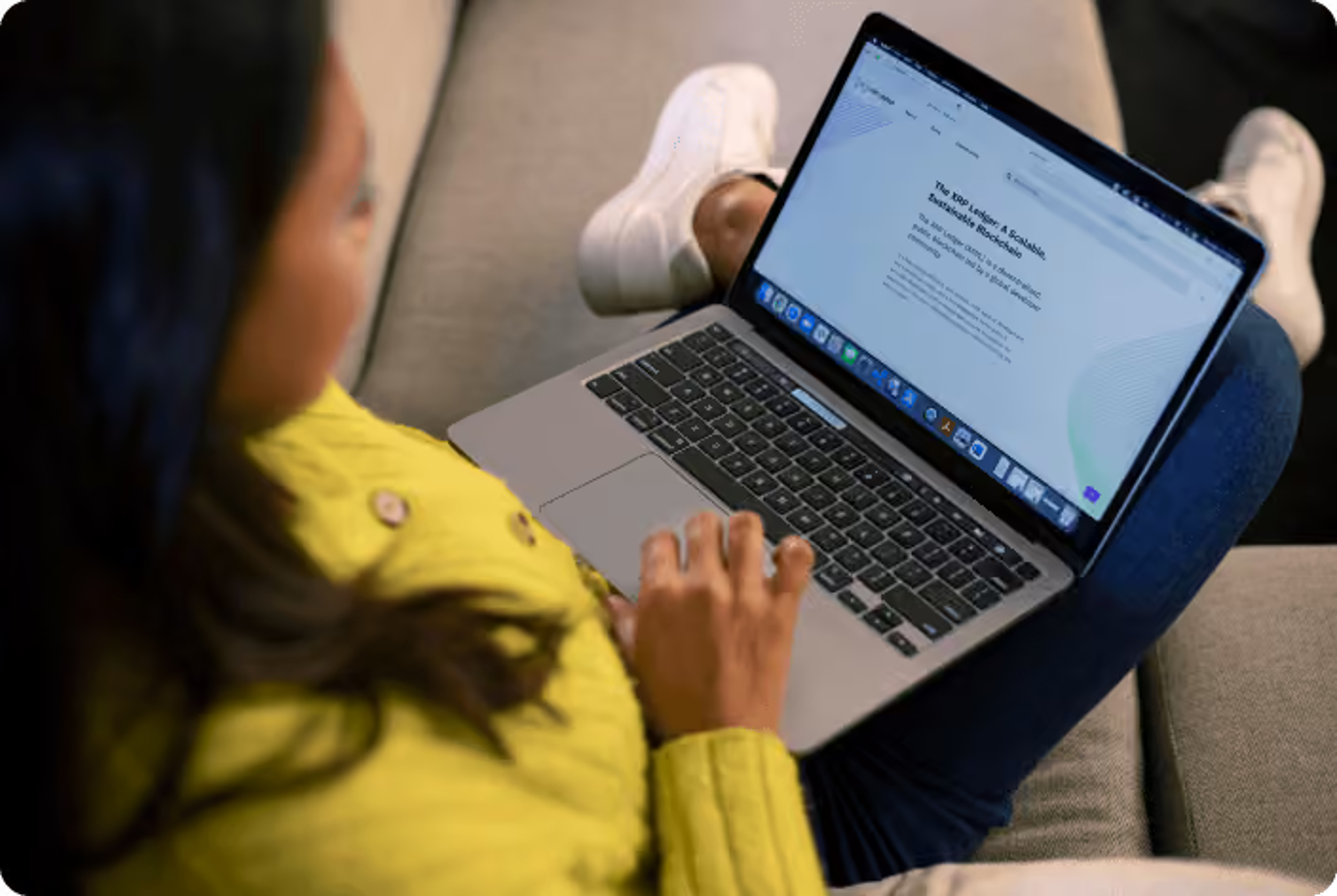 A close-up of a person sitting casually with an open laptop resting on their lap