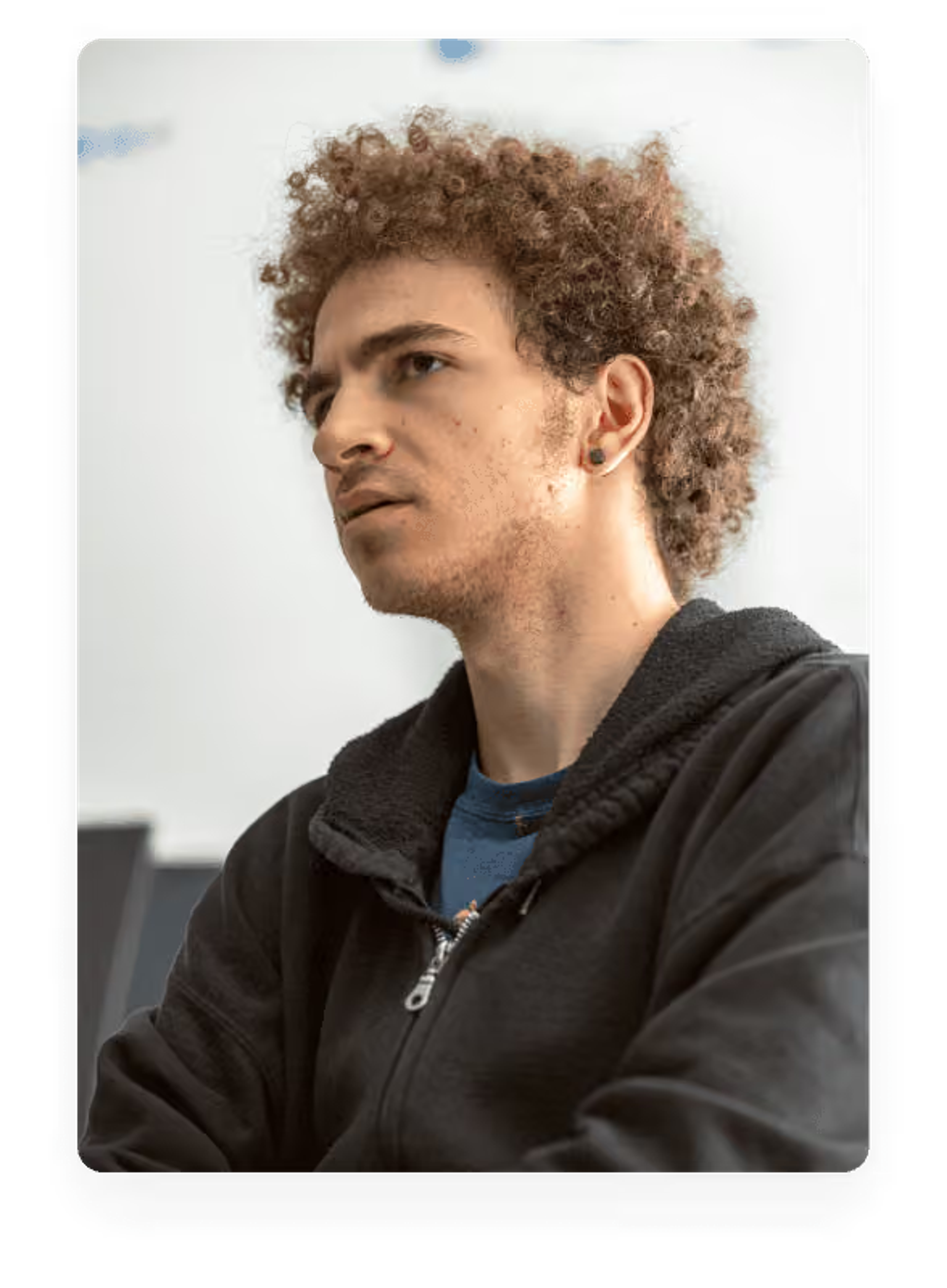 A young man with curly hair looking intently off-camera