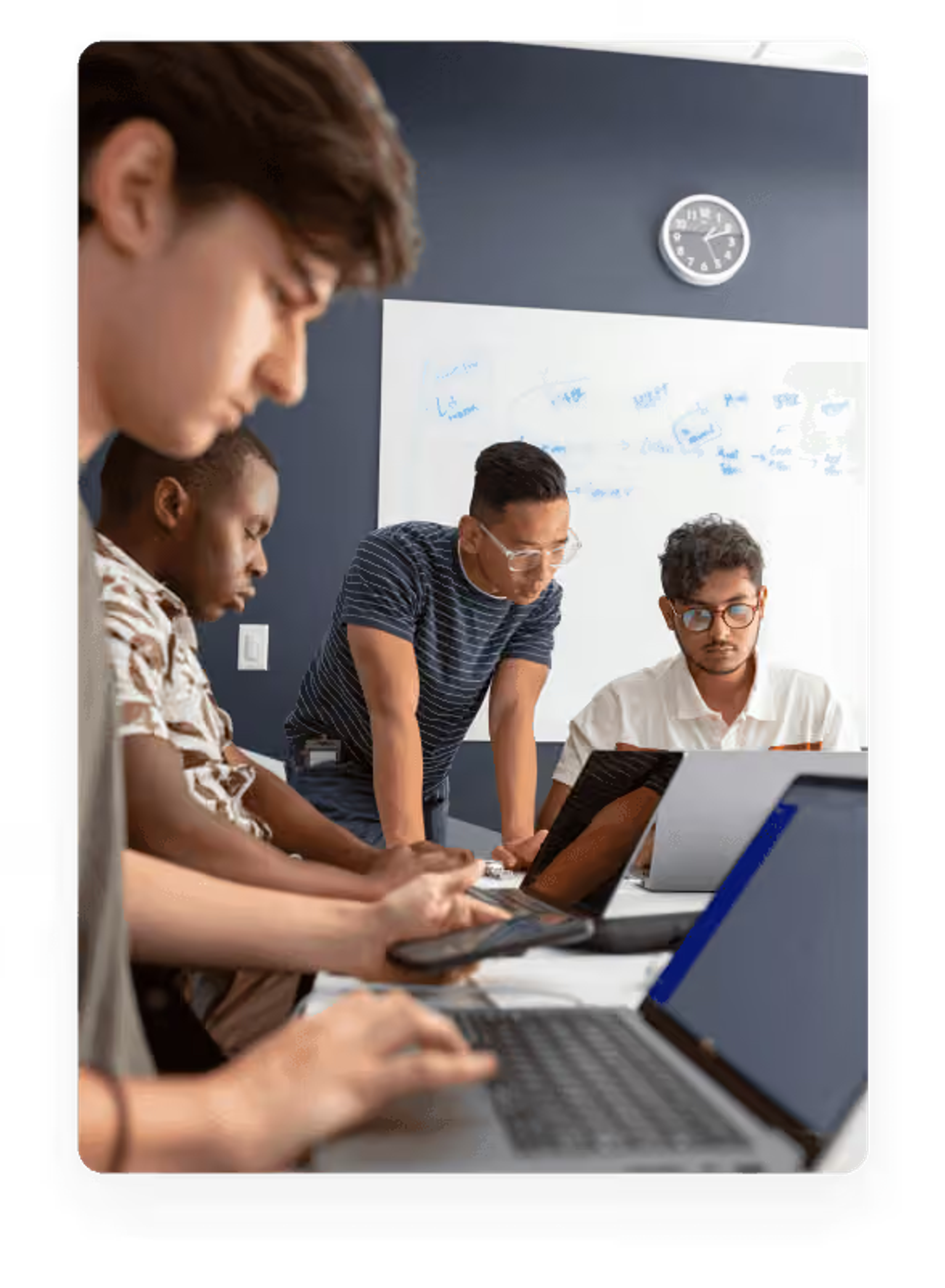 Three young men collaborating over laptops at a desk in a bright, modern office setting