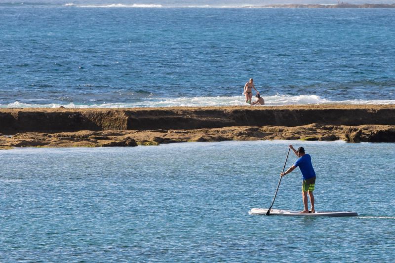 Stand-up paddleboarding on calm waters beside La Barra, Las Canteras.