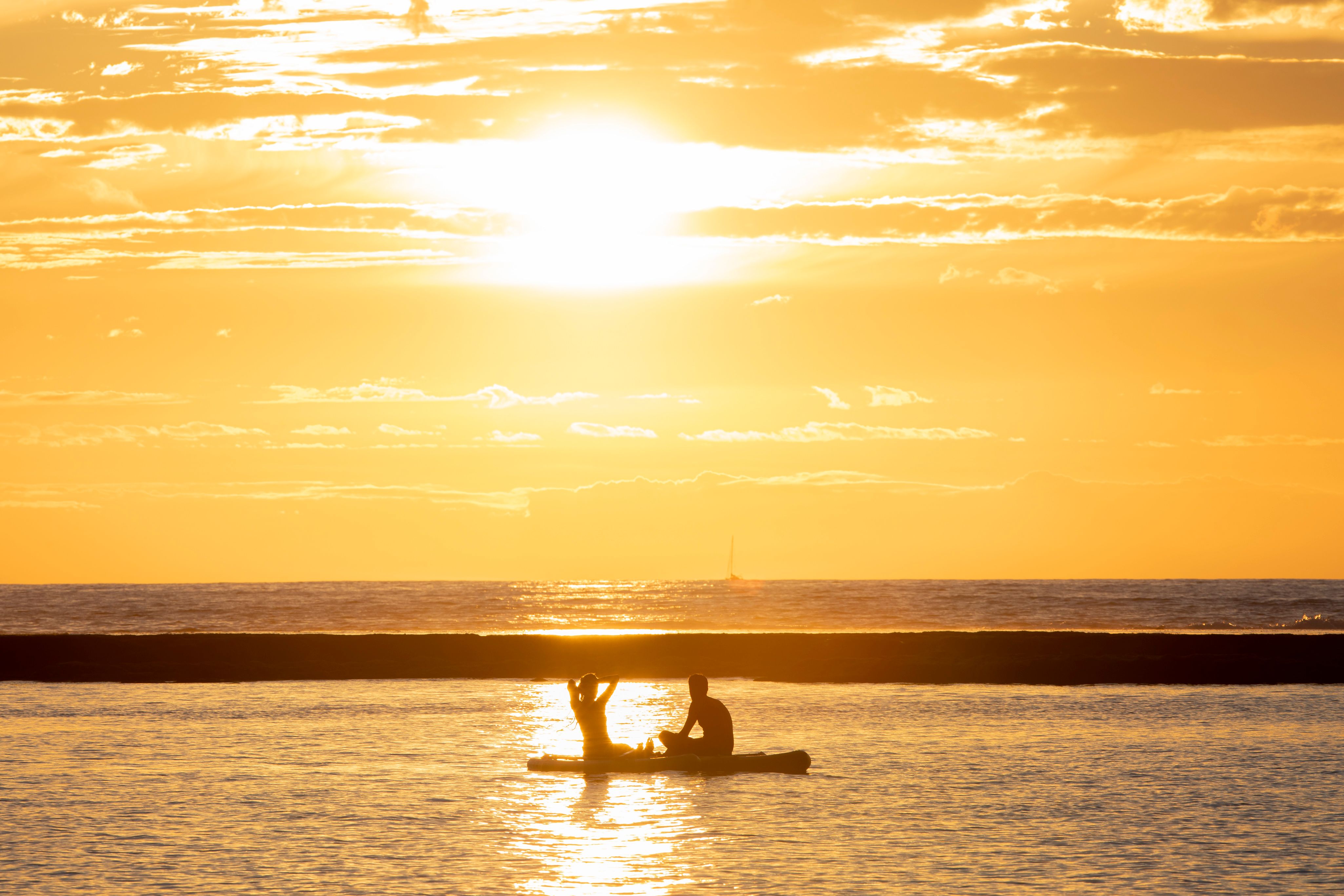 Carrying a paddleboard along the Las Canteras promenade at sunset.