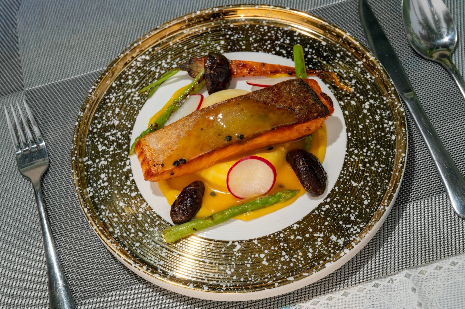 Overhead view of a fish fillet with asparagus, radish and golden sauce.
