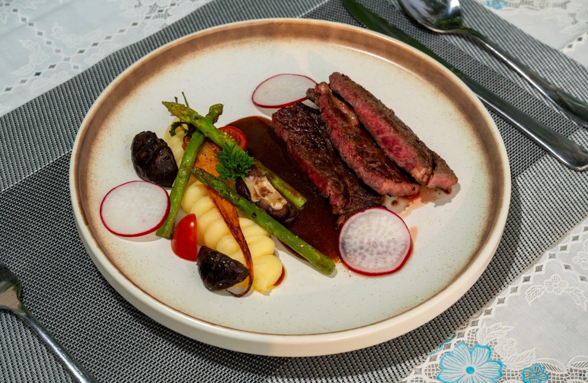 Sliced steak and vegetables on a ceramic plate at The Waterfront.