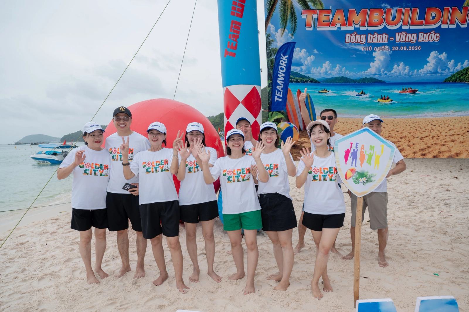 Participants in matching white shirts posing in front of a beach event backdrop.