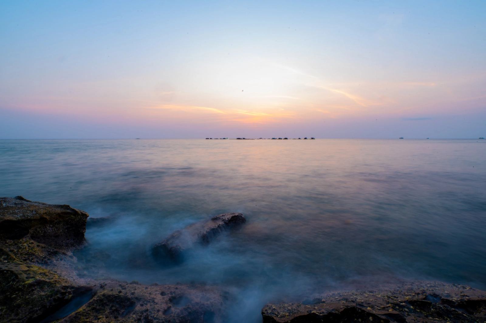 Soft evening light over the sea and the rocky shoreline.