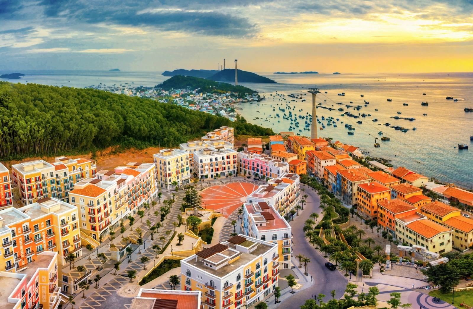 Sunset Town rooftops and the cable car route above a bay filled with boats.