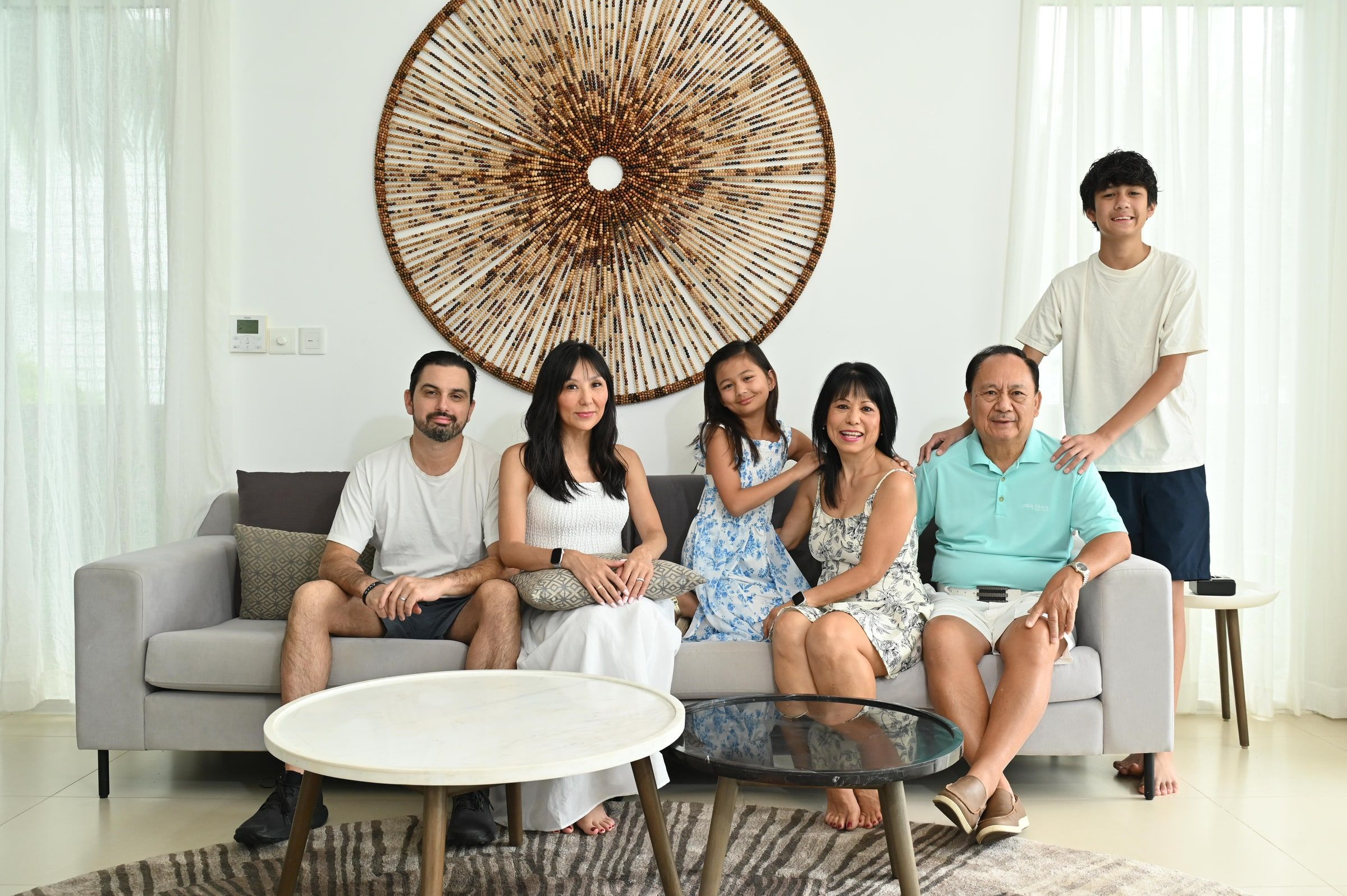 Family members of different generations posing together around a sofa in a bright lounge.