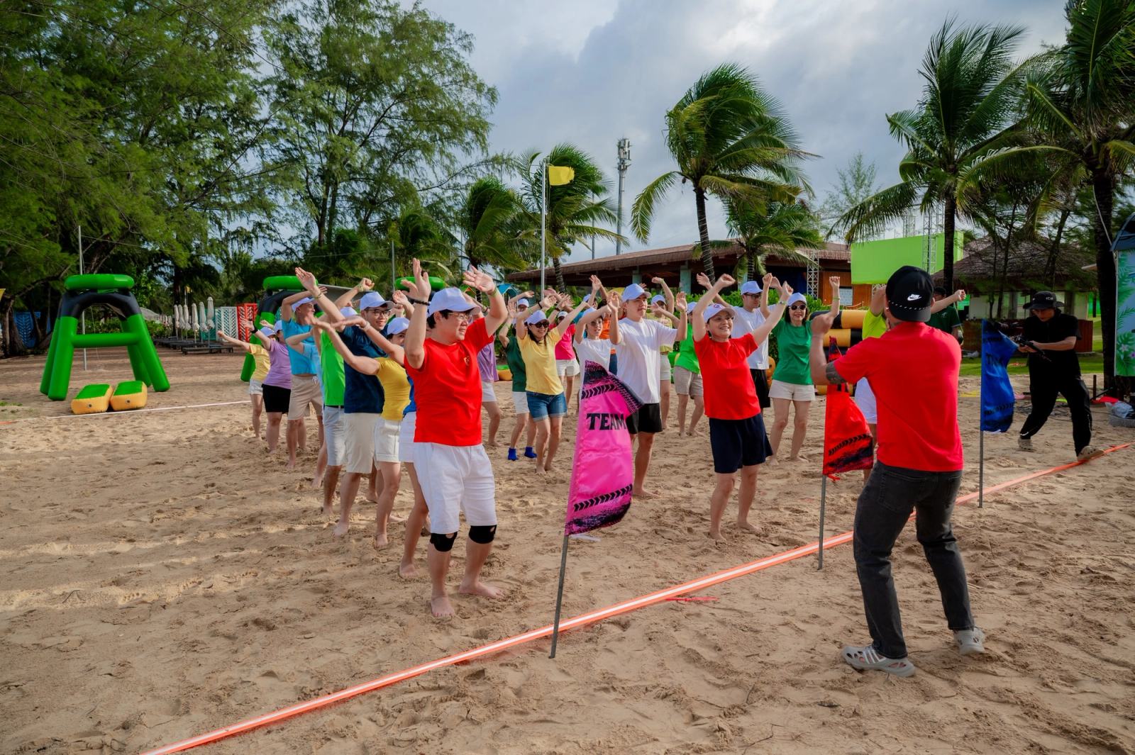 Participants taking part in a group activity on the sand beneath palm trees.