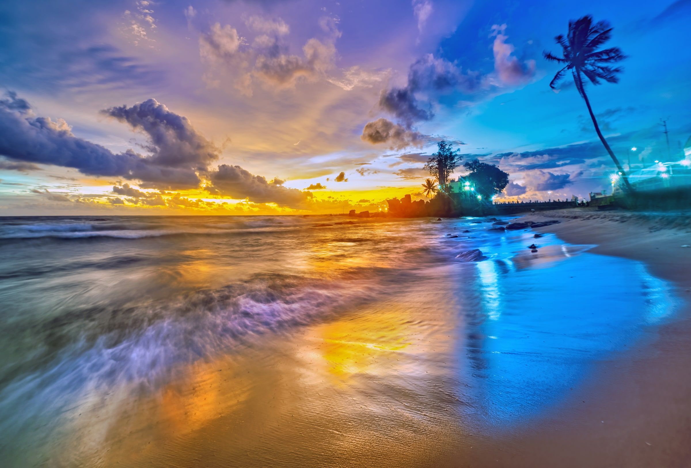 Colourful evening light over waves and palm trees along the Dinh Cau shore.