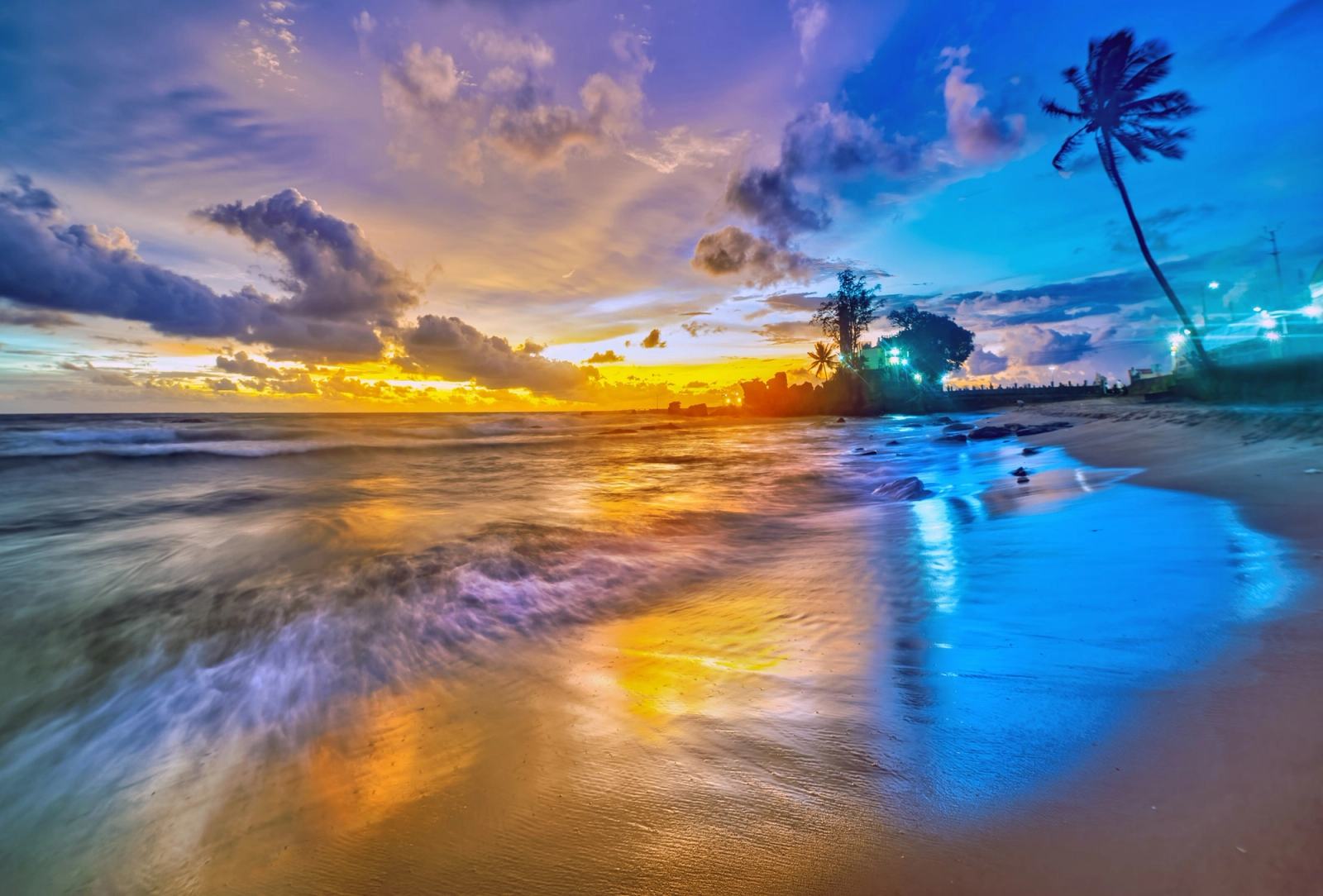 Colourful evening light over waves and palm trees along the Dinh Cau shore.
