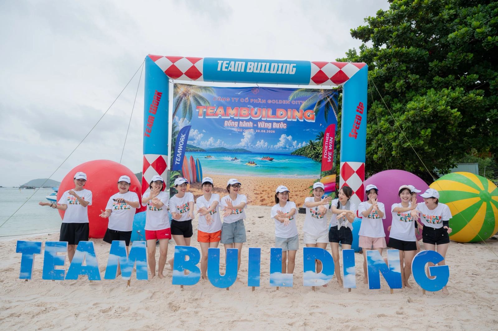 Group posing behind team-building letters beside the sea.