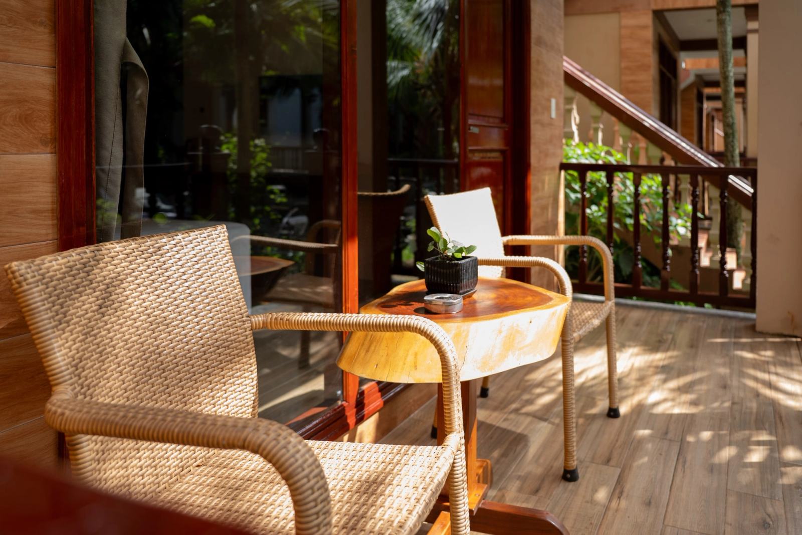 Woven chairs and a small round table on a shaded timber veranda.