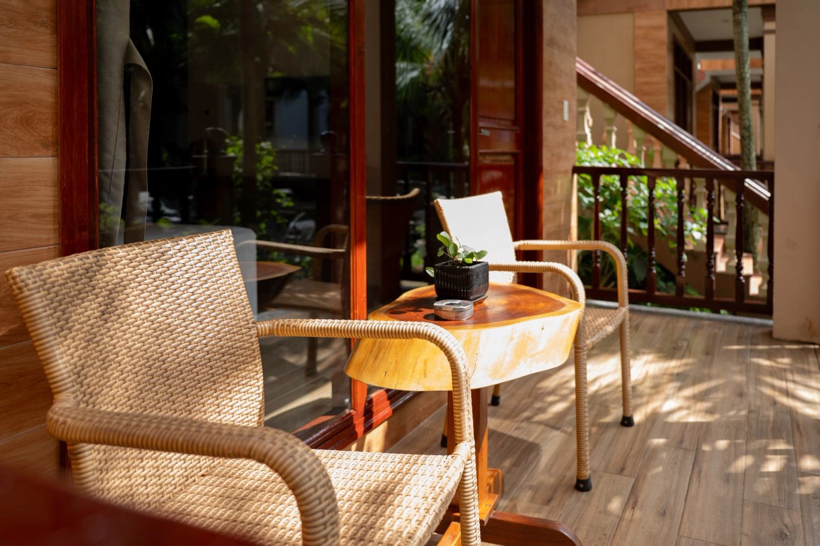 Woven chairs and a small round table on a shaded timber veranda.
