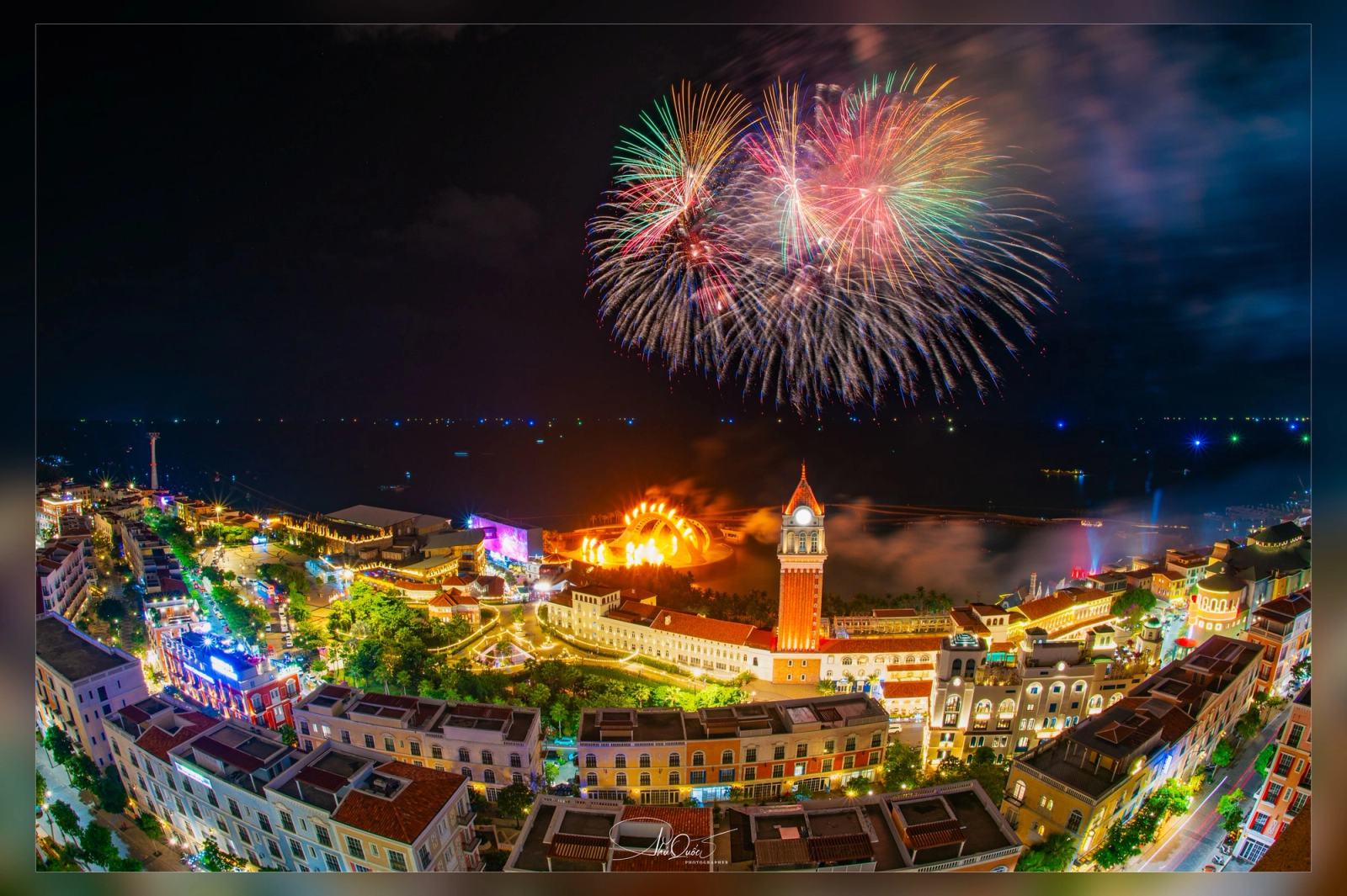 Fireworks above the illuminated waterfront and clock tower at night.