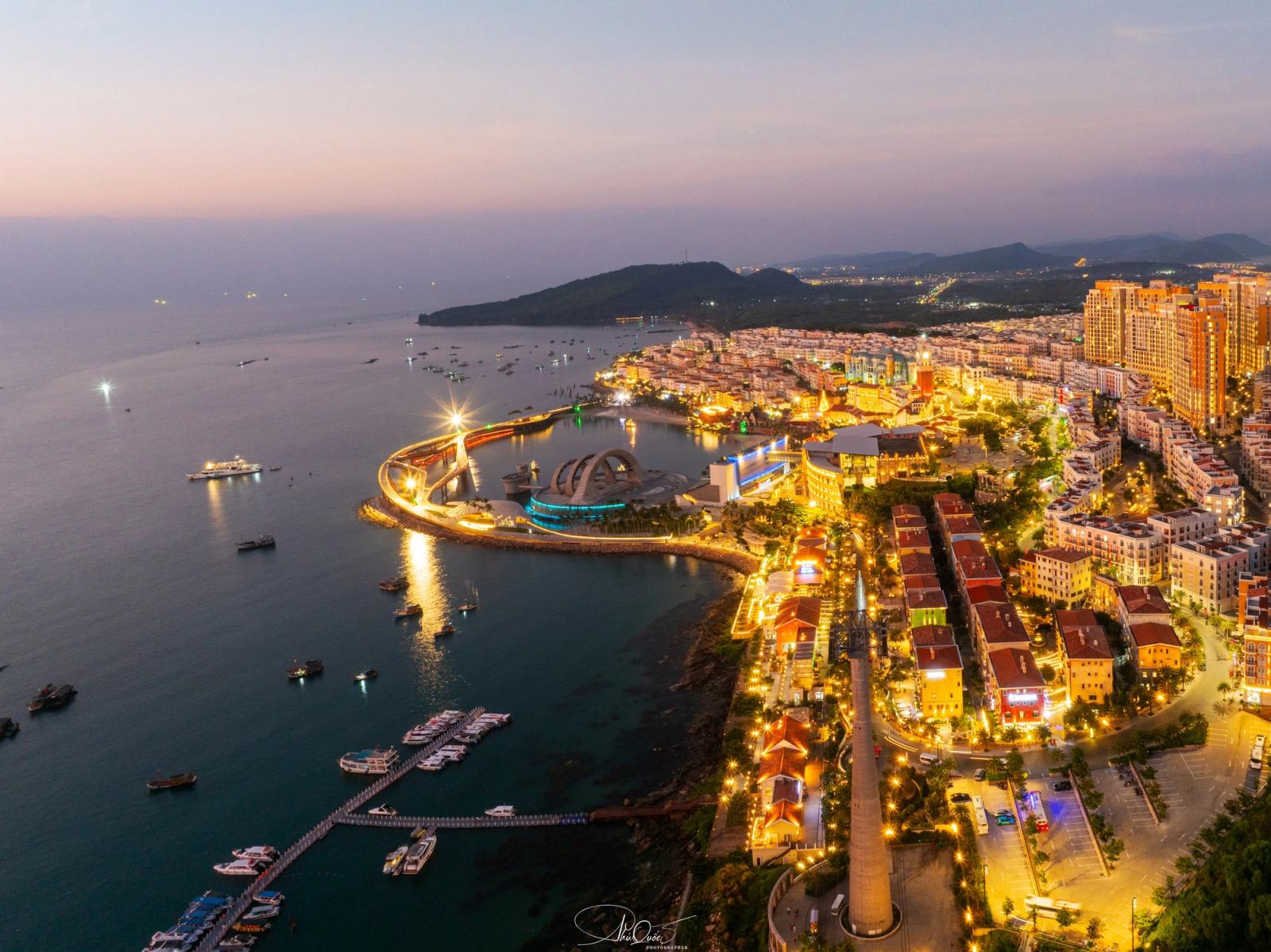Aerial view of the illuminated Sunset Town waterfront at dusk.