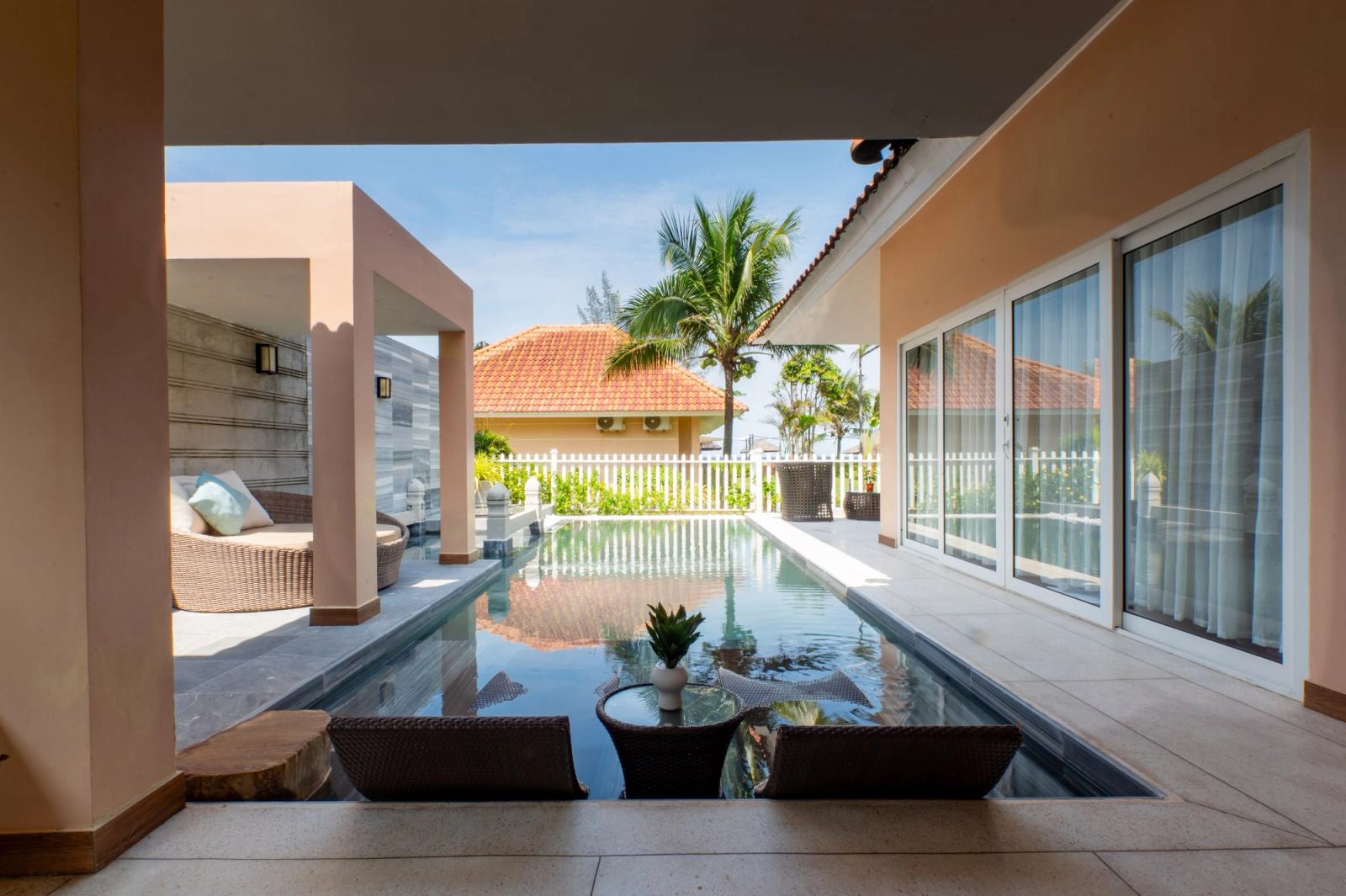Sheltered villa terrace overlooking a narrow courtyard pool beside sliding glass doors.