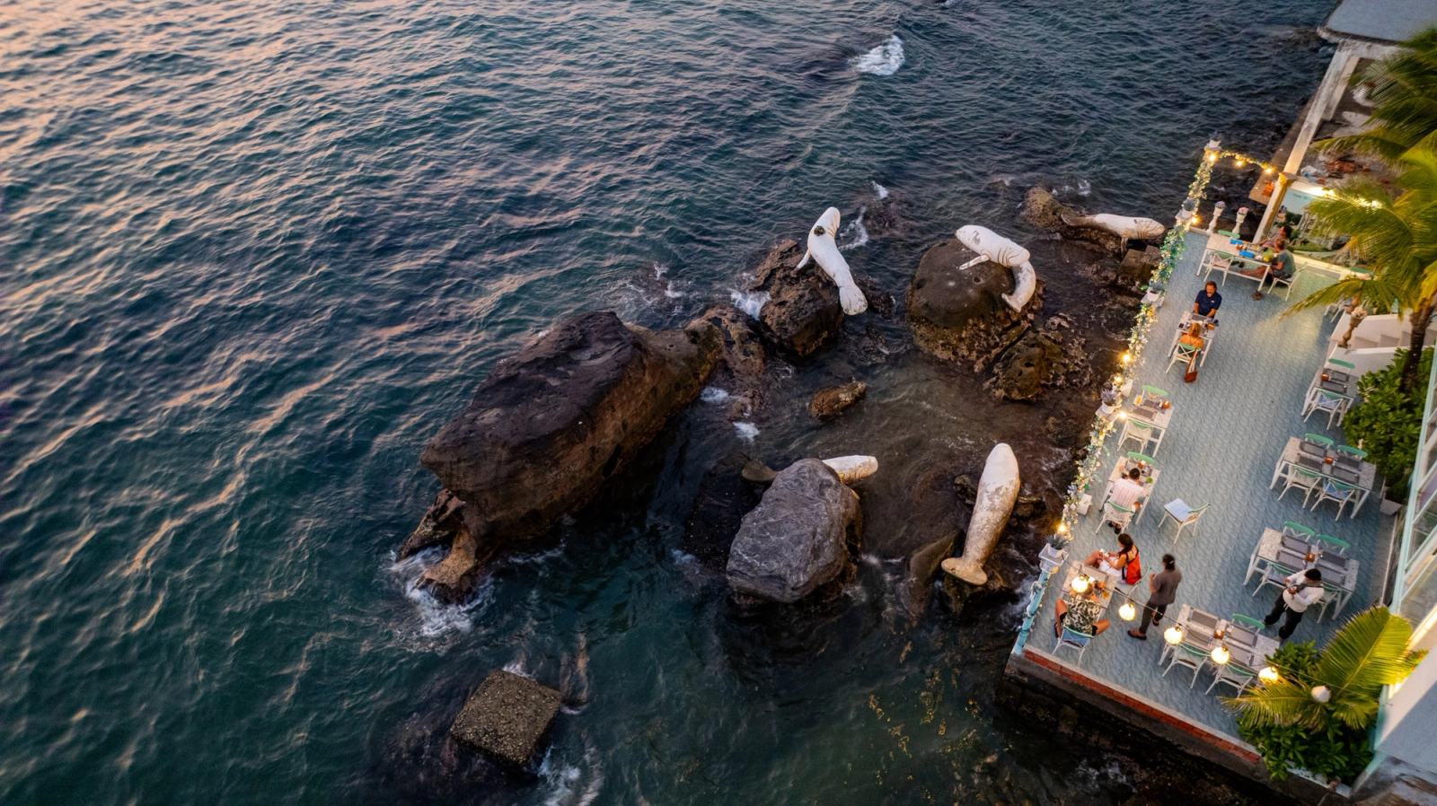 Aerial view of the rocky shoreline and illuminated terrace tables.