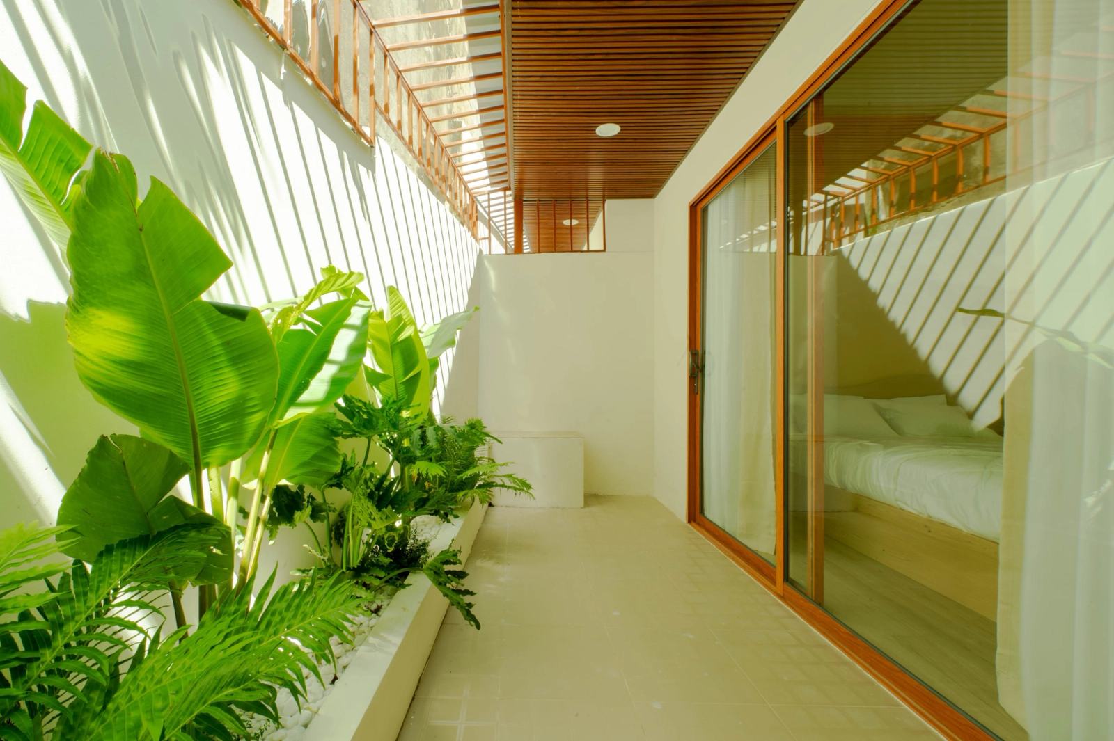 Narrow planted courtyard beside sliding glass doors and a slatted overhead screen.