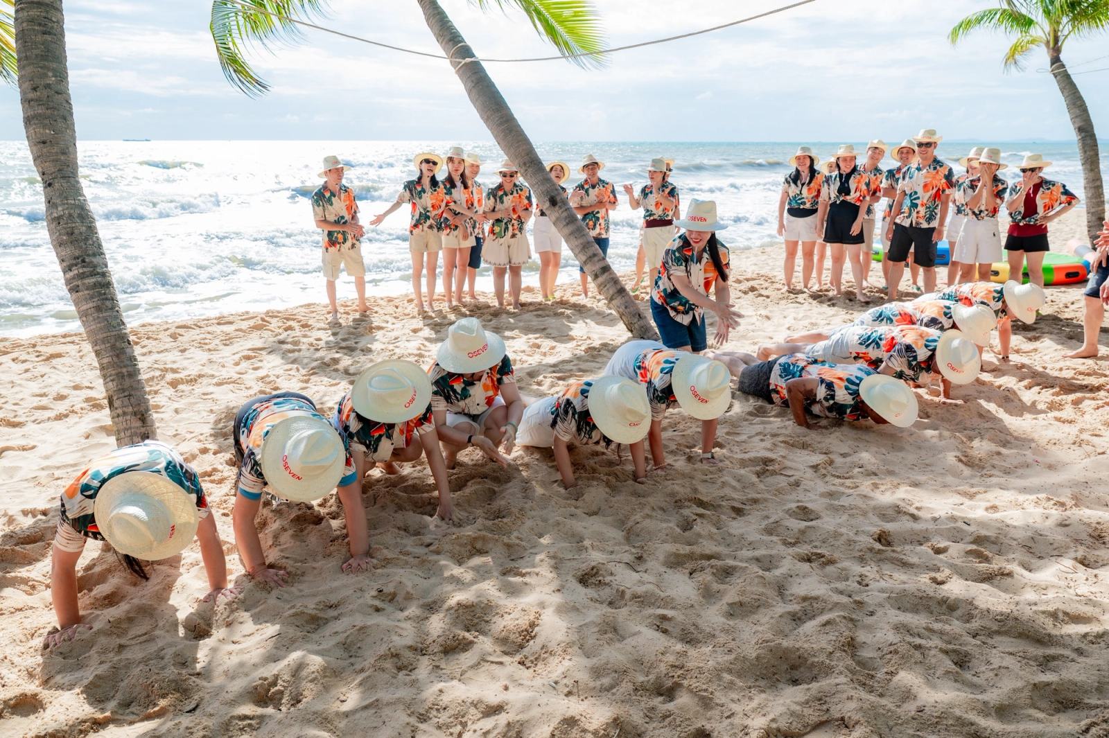 Participants completing a team challenge on the sand while others watch.
