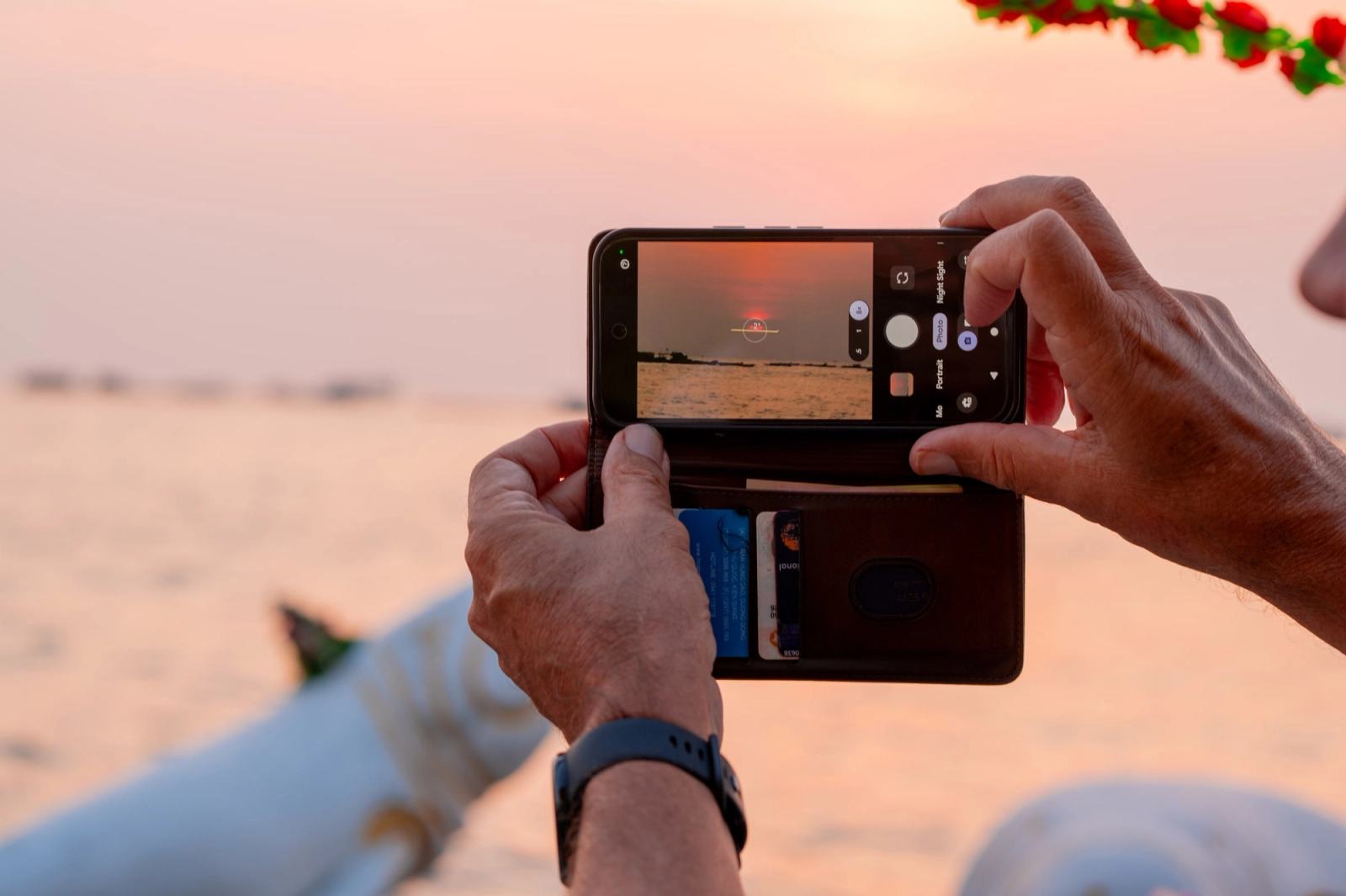 A guest photographs the sunset over the sea with a phone.