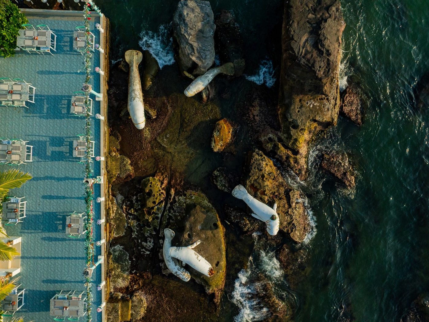 Overhead view of the dining terrace, rocky shore and fish sculptures.