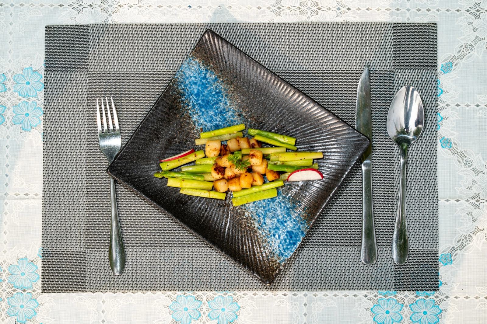 Asparagus and golden bite-sized pieces arranged on a blue-and-black square plate.