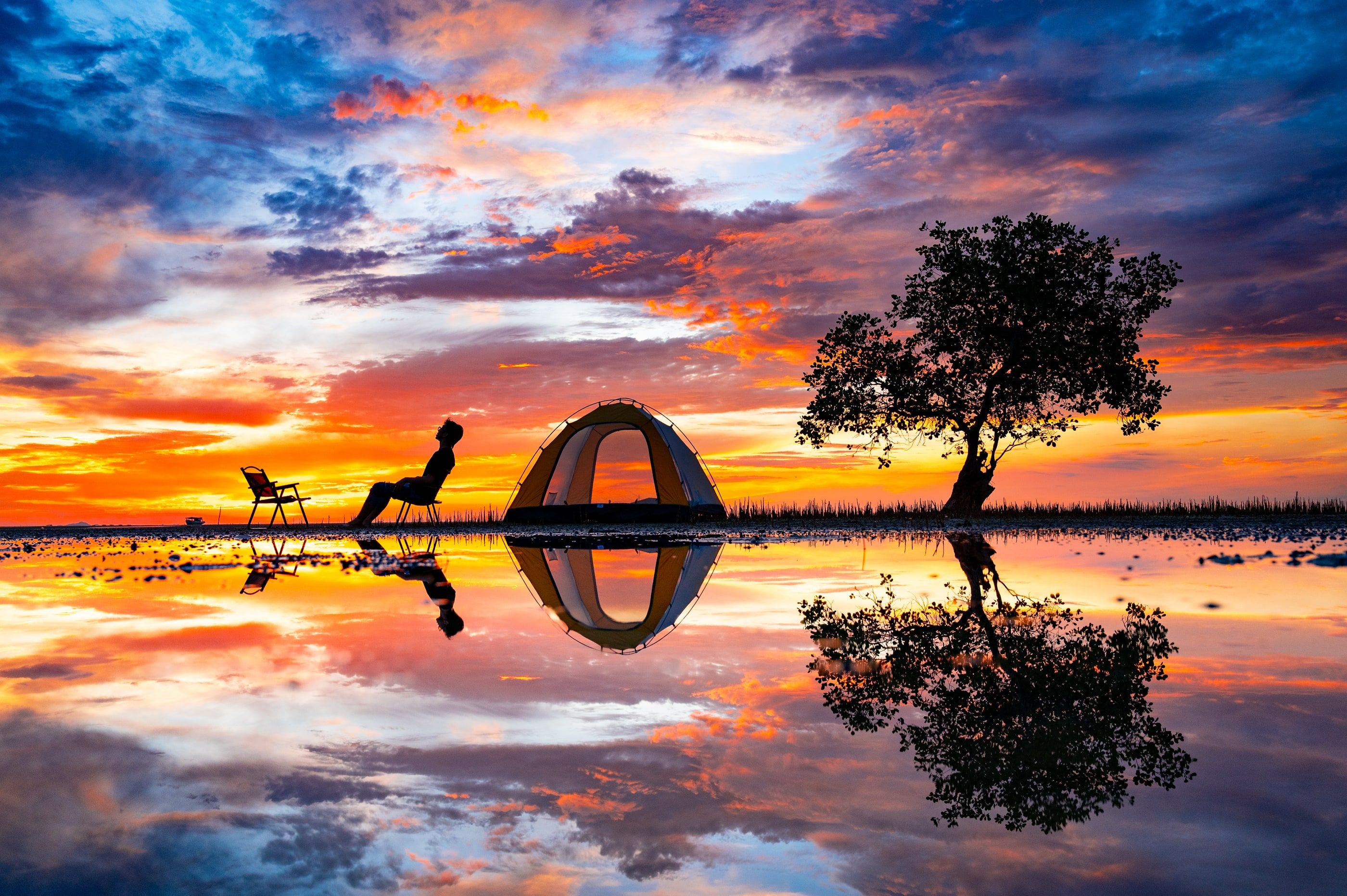 A tent and traveller reflected beneath an evening sky.
