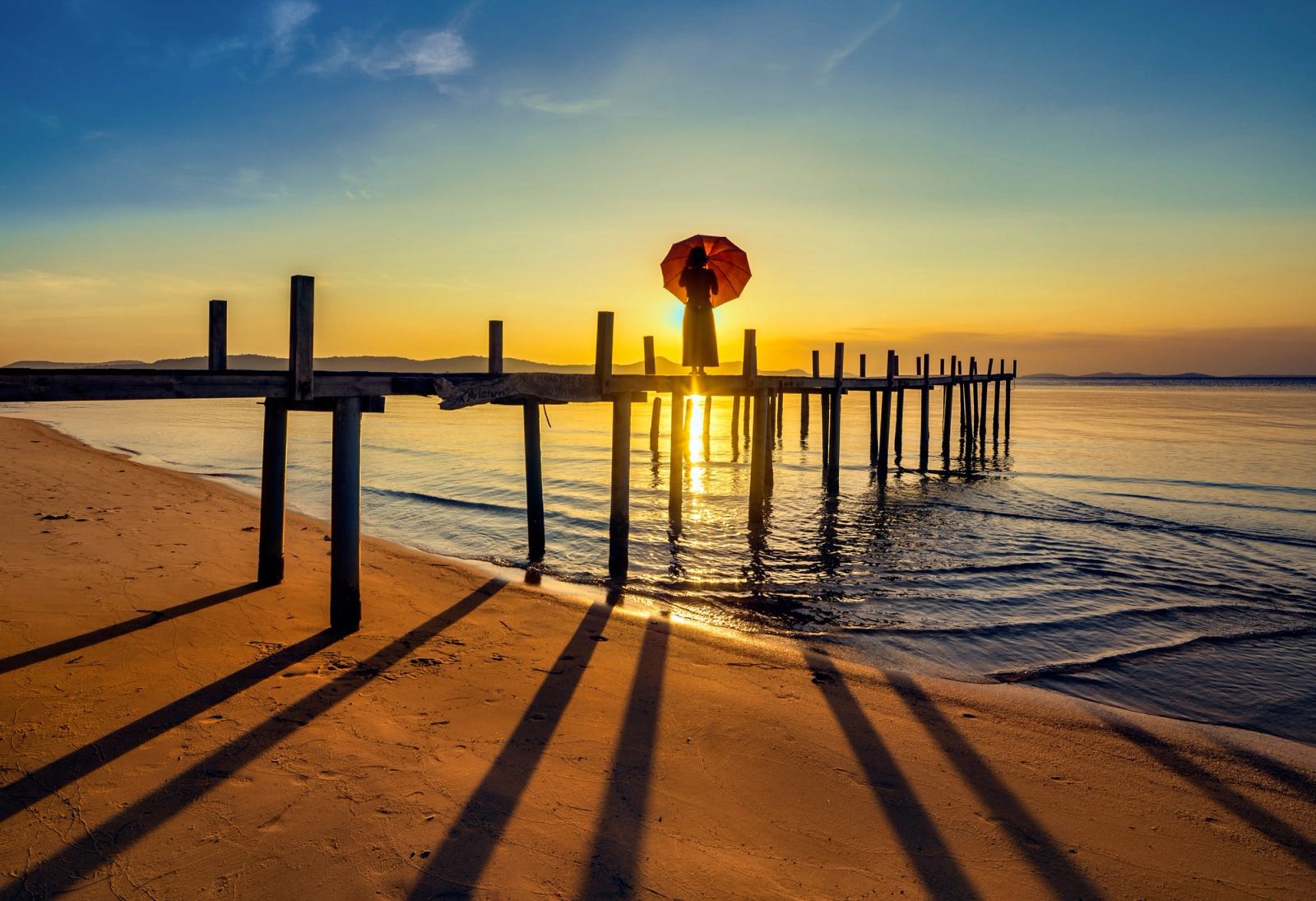 A person with an umbrella on a wooden bridge at Ham Rong in golden light.