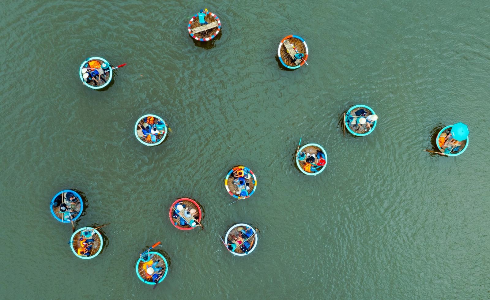Round basket boats carrying passengers scattered across the river, seen from above.
