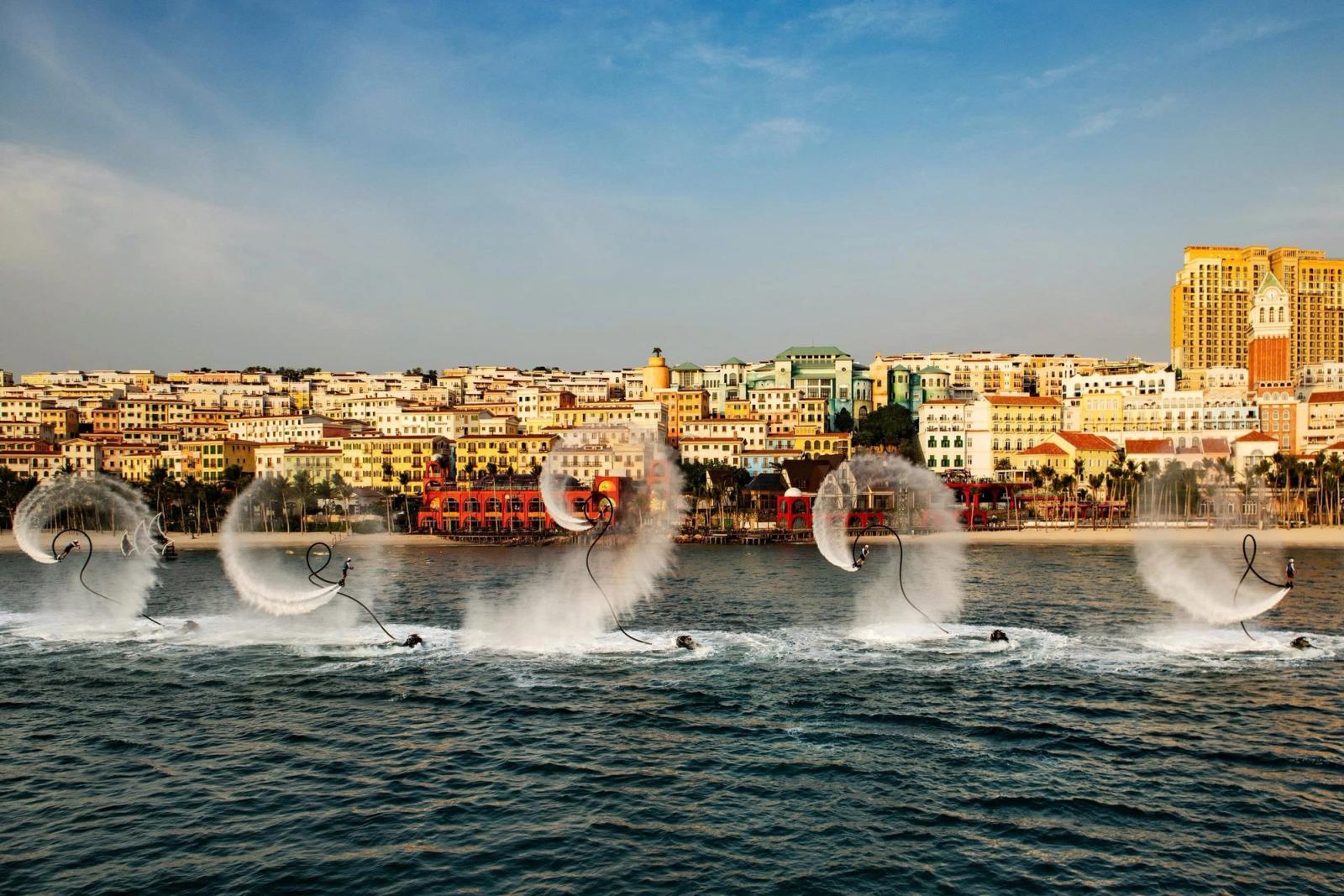 Water-sport performers creating arcs of spray in front of Sunset Town.