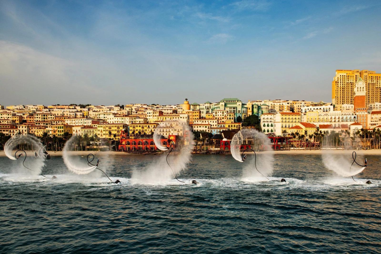 Water-sport performers creating arcs of spray in front of Sunset Town.