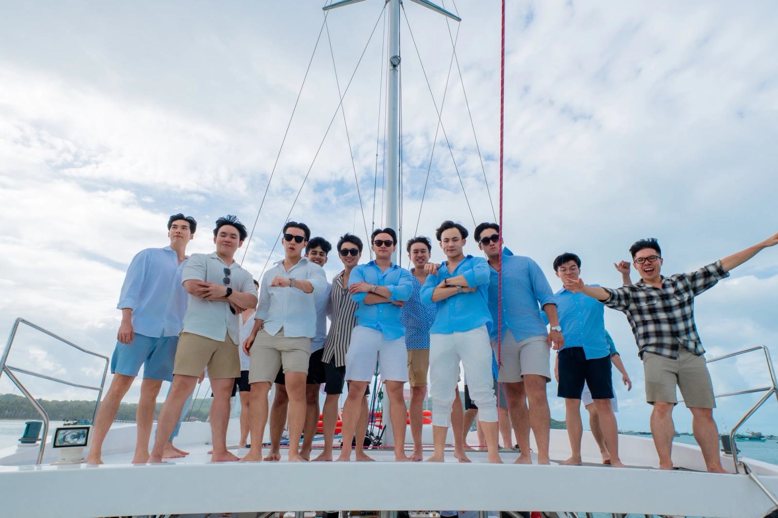 Friends standing together beneath the mast on a yacht deck.