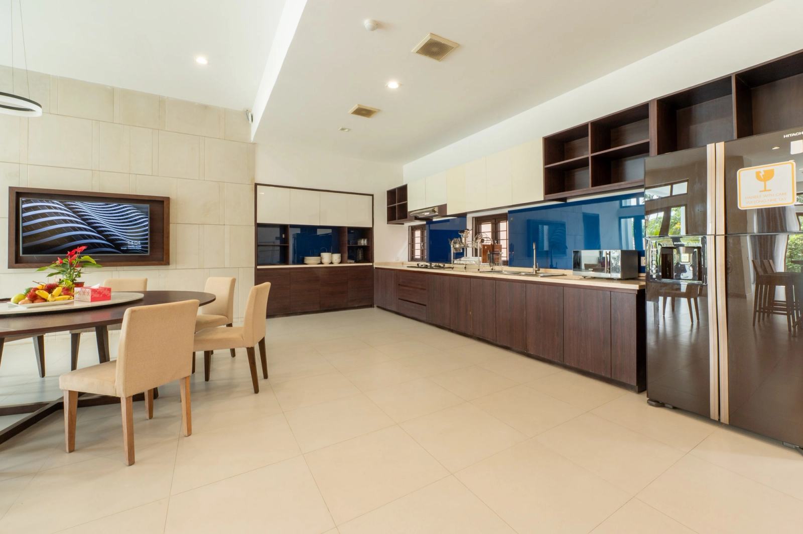 Open kitchen and dining area with dark cabinetry, a blue backsplash and a large refrigerator.