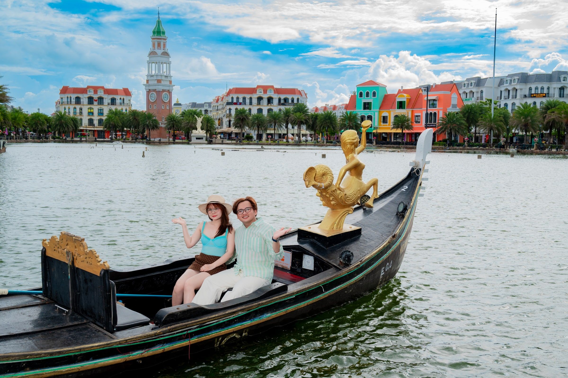 Couple seated together in a gondola on a canal surrounded by colourful buildings.