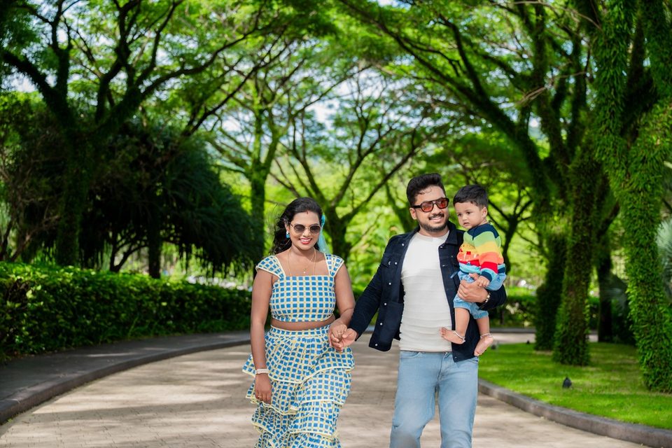 Two adults and a child beneath a green canopy.