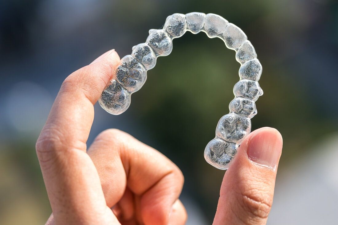 Male hand holds Invisalign clear aligner in San Francisco